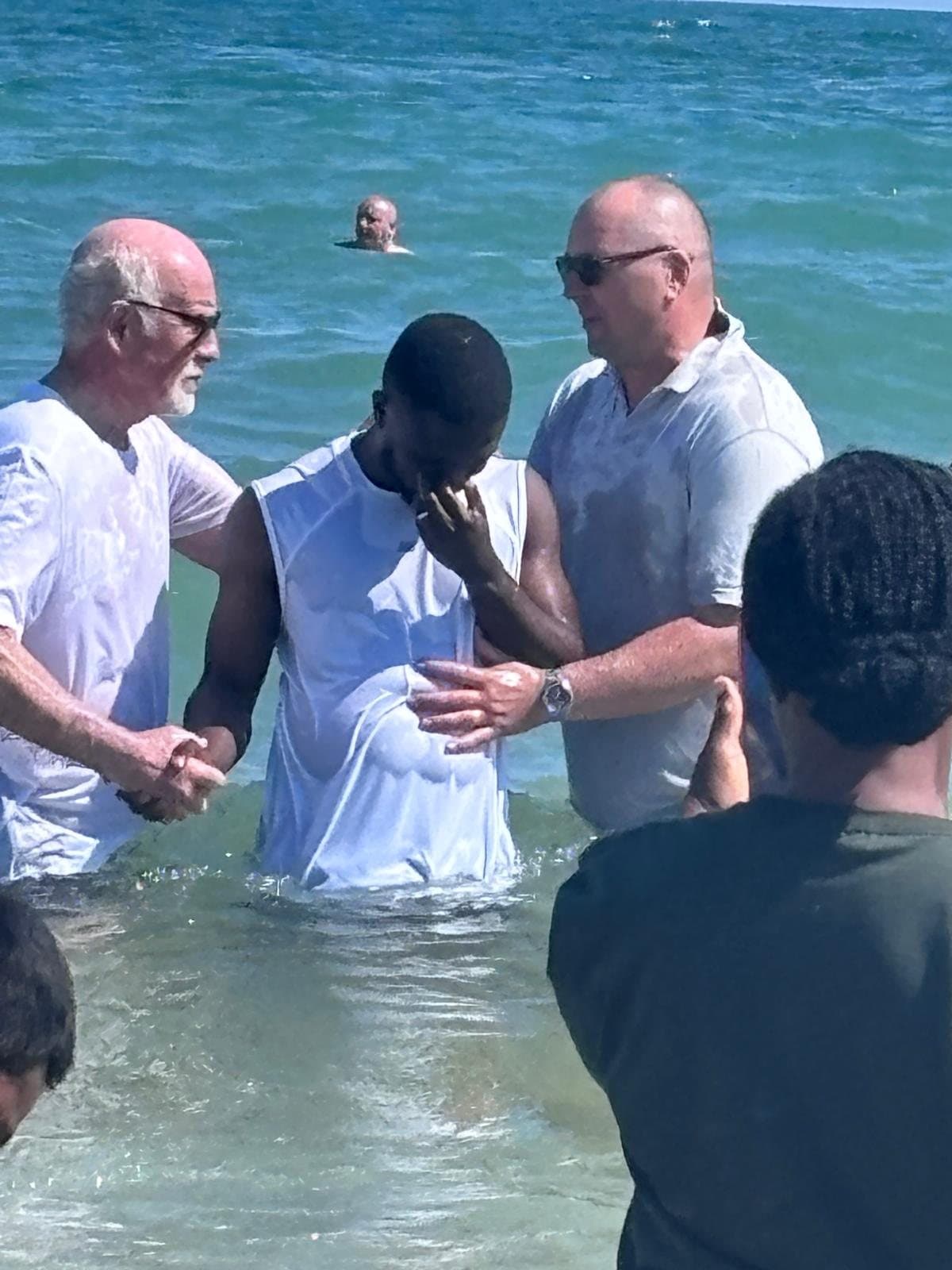 A believer being baptised in the sea during a church seaside outing