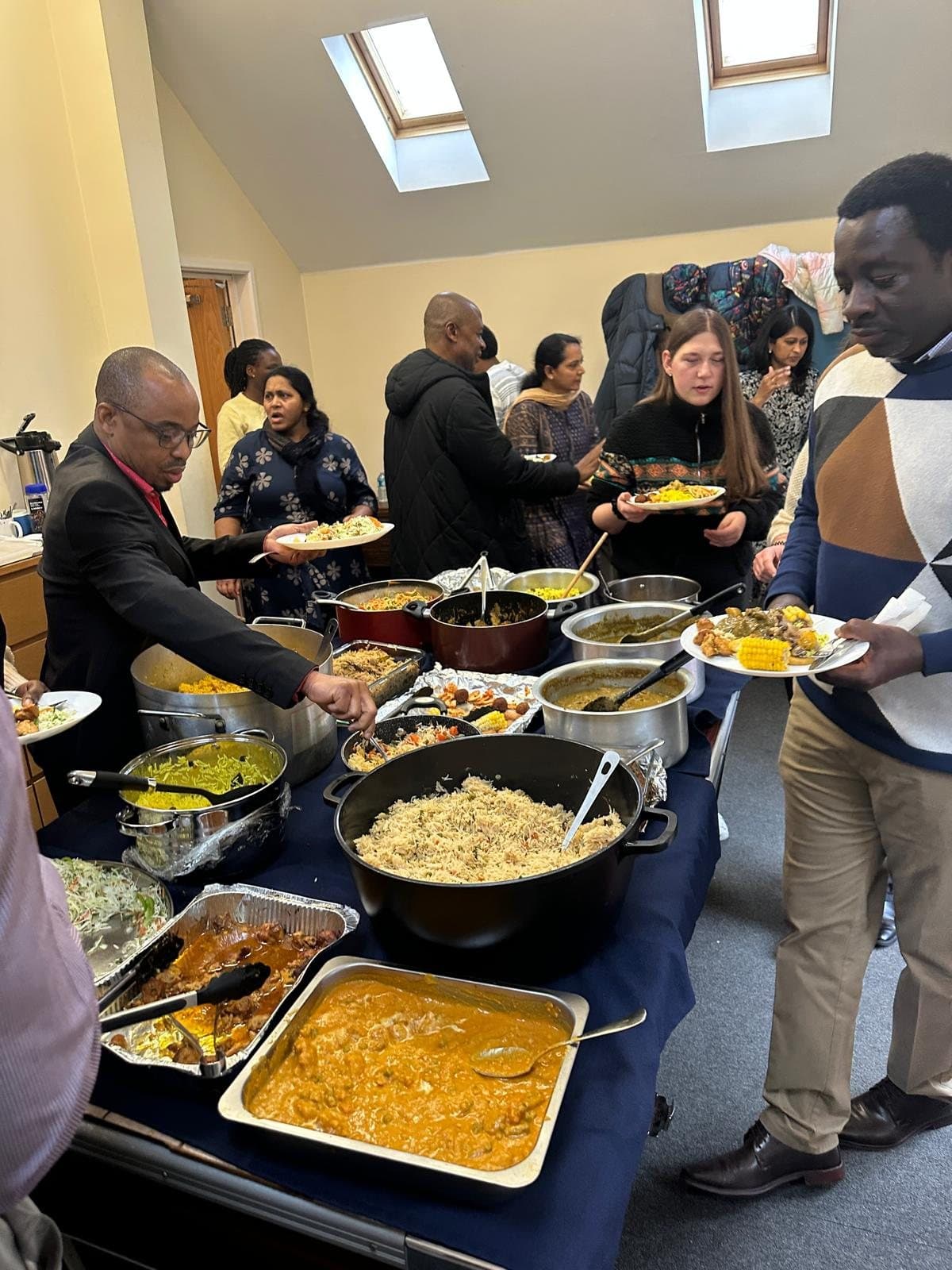 Church members serving themselves from a bring-and-share table of dishes from many cultures