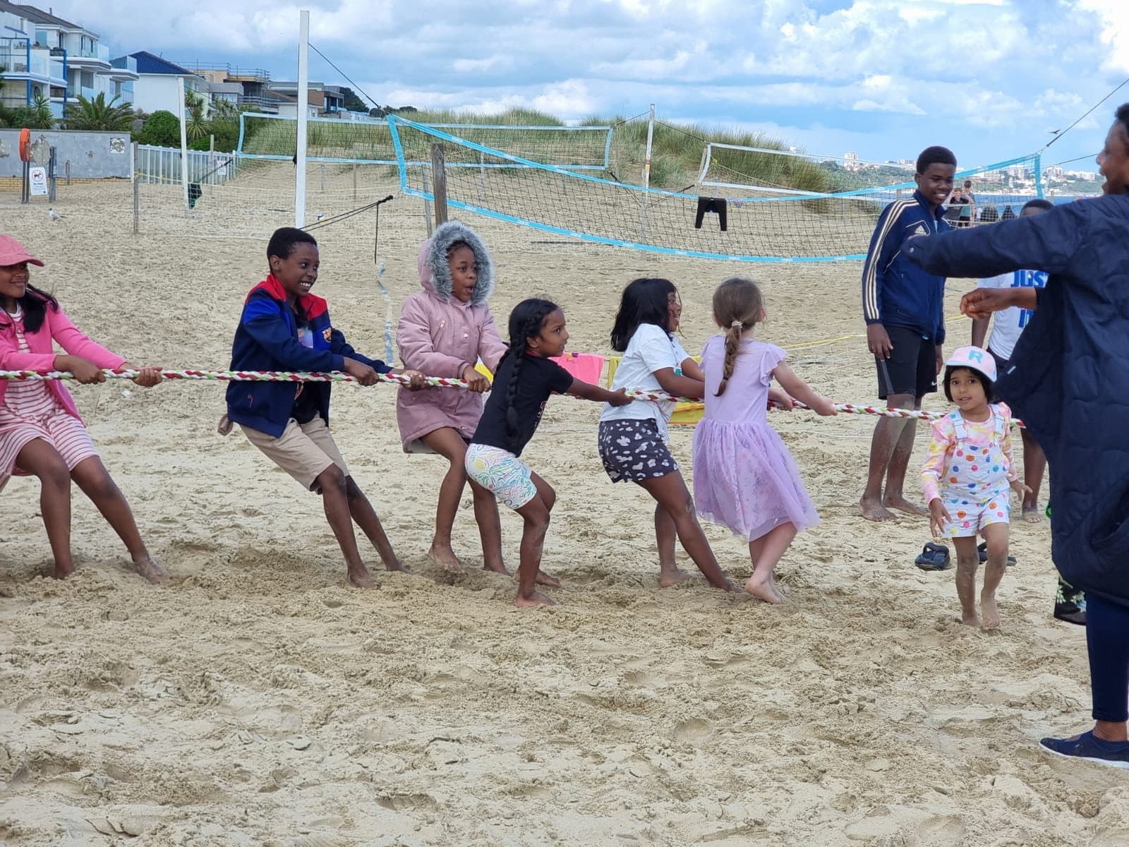 Children playing tug-of-war on the beach during a church seaside outing